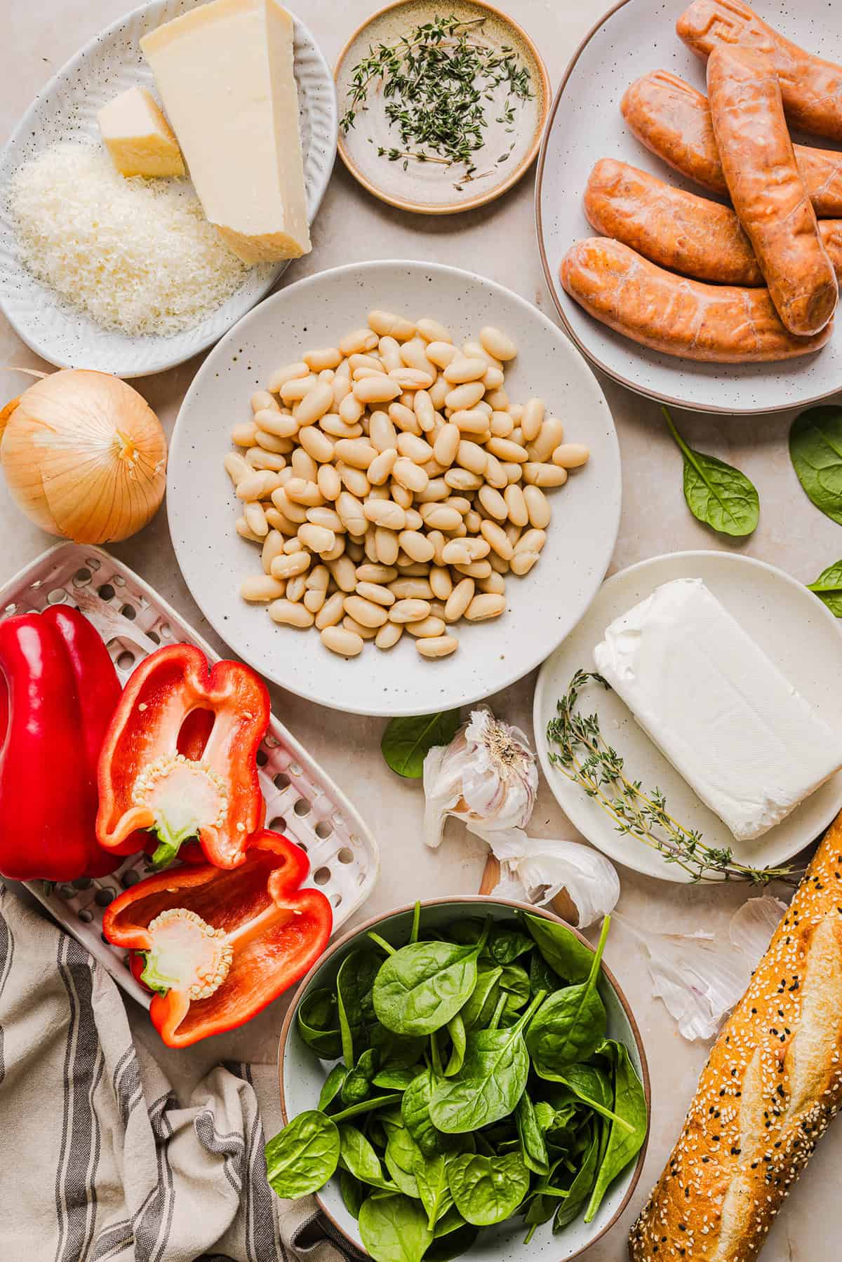 This Cheesy Sausage Bean Dip is the ultimate party appetizer! Made with flavorful spicy sausage, sautéed onions, bell peppers, garlic and spinach, along with cream cheese and white beans. Topped with freshly grated parmesan cheese and served with toasted bread or Frito corn chips!