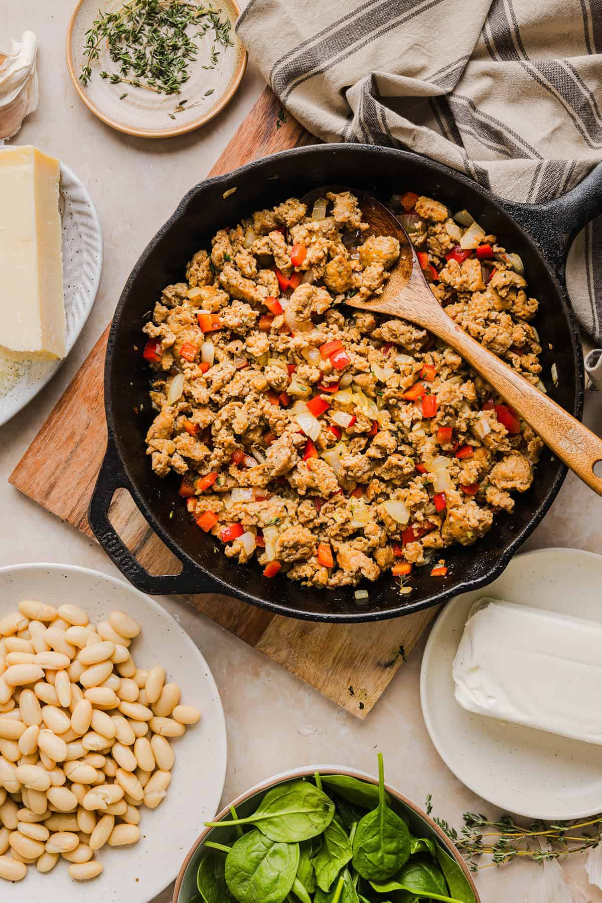 This Cheesy Sausage Bean Dip is the ultimate party appetizer! Made with flavorful spicy sausage, sautéed onions, bell peppers, garlic and spinach, along with cream cheese and white beans. Topped with freshly grated parmesan cheese and served with toasted bread or Frito corn chips!