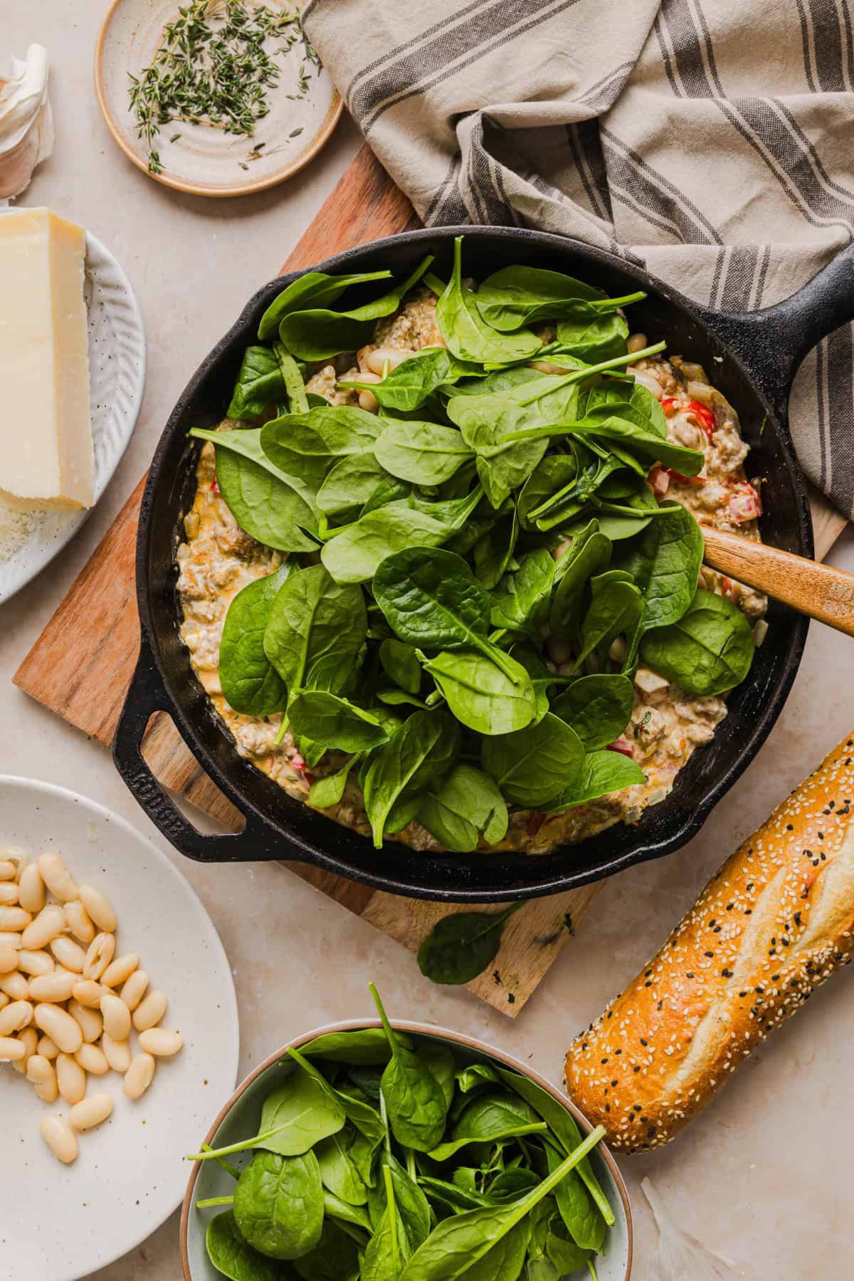 This Cheesy Sausage Bean Dip is the ultimate party appetizer! Made with flavorful spicy sausage, sautéed onions, bell peppers, garlic and spinach, along with cream cheese and white beans. Topped with freshly grated parmesan cheese and served with toasted bread or Frito corn chips!