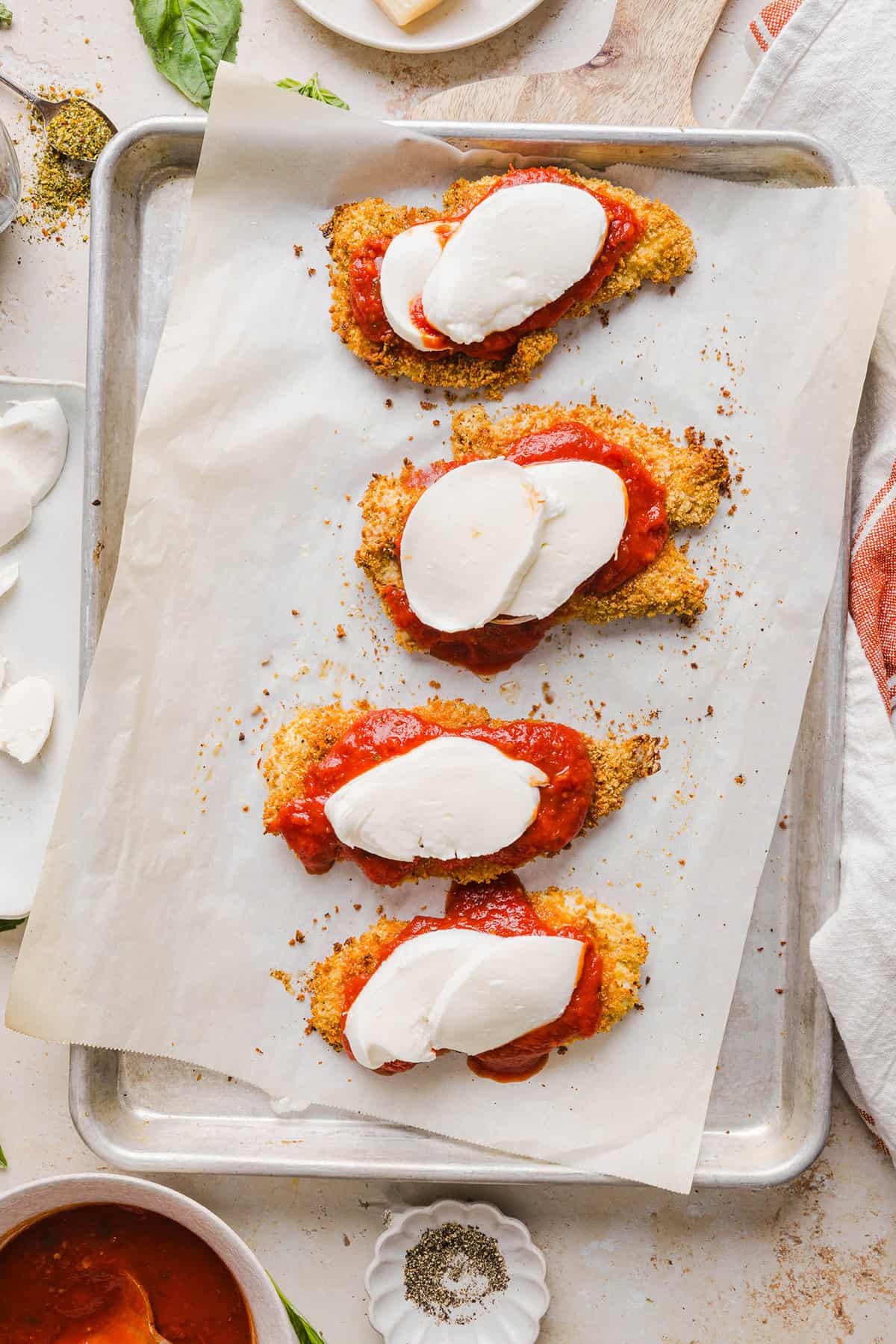 Easy Baked Chicken Parmesan made with tender juicy chicken, rich marinara sauce and melty cheese with a crisp coating that tastes delicious! This chicken is baked, not fried, and easily comes together in under 30 minutes!